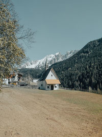 Houses on field by mountains against sky