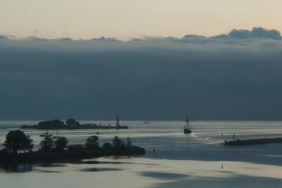 Lone boat in calm sea against clouds