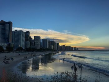 Scenic view of sea by buildings against sky during sunset