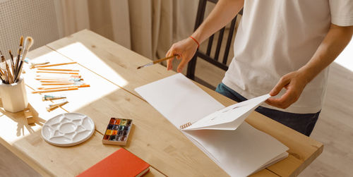 Creative man in a white t-shirt holding sketchbook and pencil. diy. real art maker in action