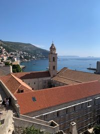 Buildings by sea against blue sky