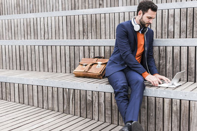 Usa, new york city, businessman sitting on stairs using digital tablet