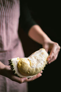 Close-up of hand holding ice cream cone against black background