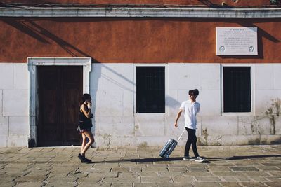 Woman standing on footpath in front of building