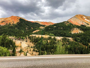 Road by trees and mountains against sky
