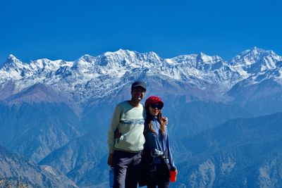 Portrait of couple standing against snowcapped mountains