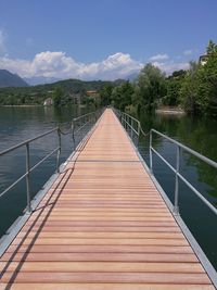 Footbridge over lake against sky