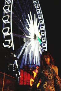 Woman standing at illuminated amusement park