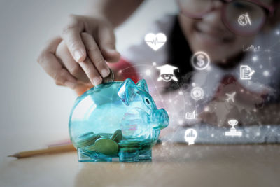 Digital composite image of hands putting coin in piggy bank