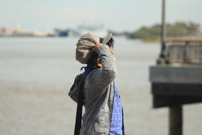 Side view of boy gesturing while standing at beach