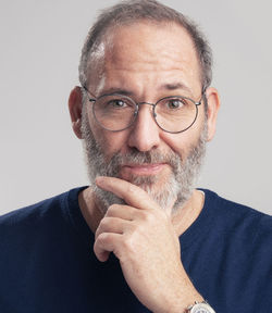 Portrait of man with hand on chin against gray background
