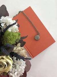 High angle view of red rose on table against white background