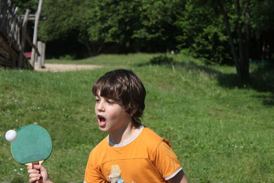 Teenage boy screaming while playing table tennis in park