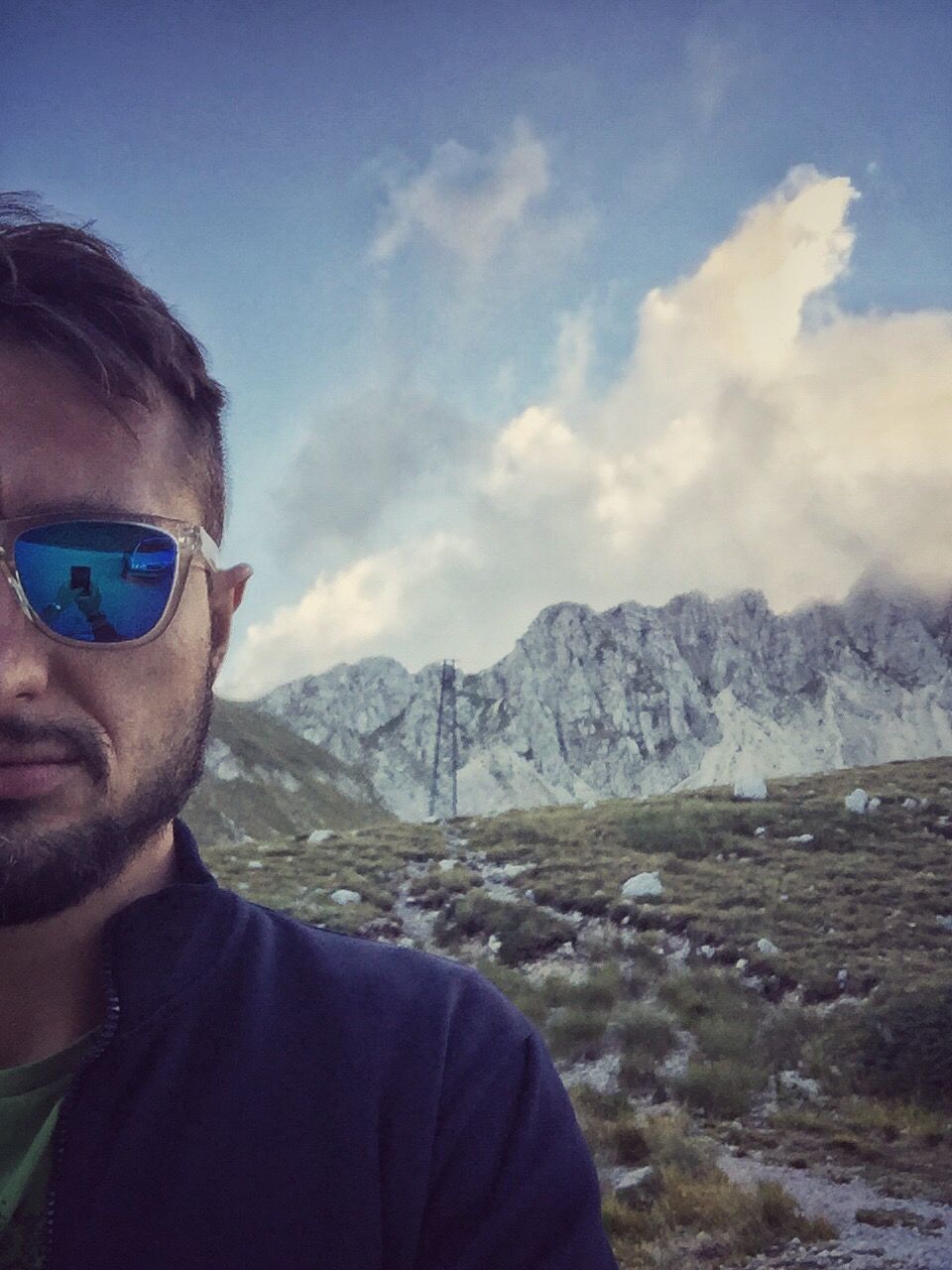 mountain, cloud - sky, sky, leisure activity, headshot, mountain range, lifestyles, hiking, scenics, young adult, tranquil scene, human face, nature, tourist, knit hat, water, beauty in nature, vacations, cliff, exploration, outdoors, tranquility, adventure