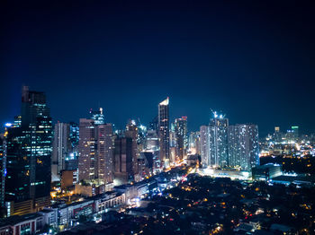 Illuminated cityscape against clear blue sky at night