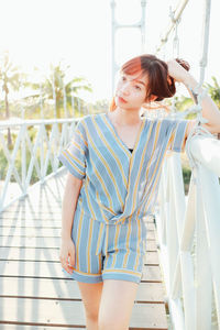 Woman looking away while standing against railing