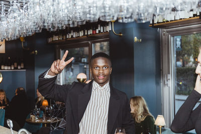 Portrait of man doing peace sign in bar