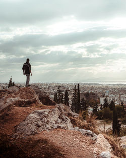 Man standing on rock against sky