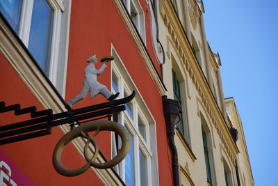 Low angle view of statue by building against clear sky