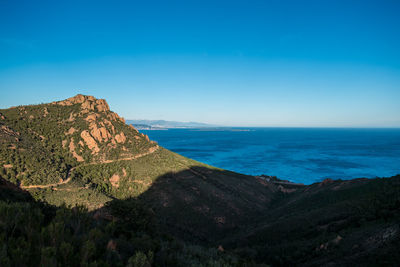 Scenic view of sea and mountains against blue sky