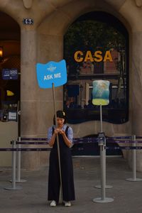 Full length of woman holding umbrella standing on street