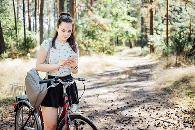 Best cycling apps. bike tracker. young woman with backpack riding bike and looking in cell phone on