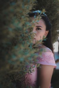 Portrait of young woman standing by plants