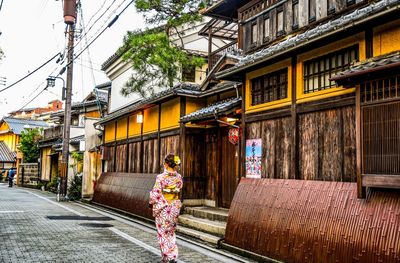 Rear view of woman walking on street amidst buildings in city