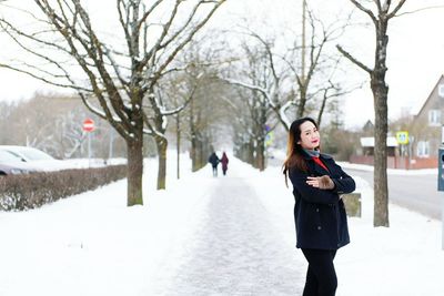 Portrait of woman standing on snow covered footpath in city