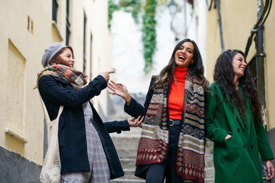 Low angle view of friends laughing on staircase amidst building