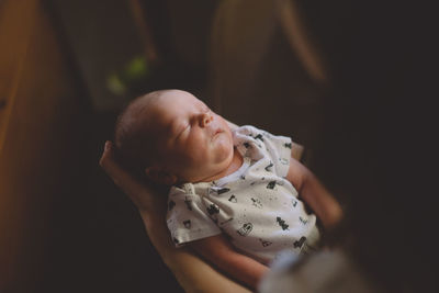 High angle view of mother holding sleeping baby boy at home