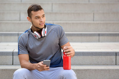 Young man using mobile phone while sitting on staircase