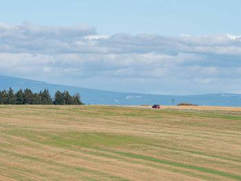 Rural landscape with car and agricultural fields on spring hills in north region of czech republic