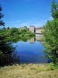 Lake by buildings against blue sky