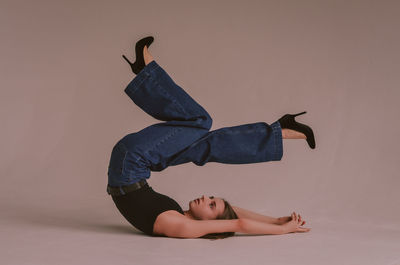 Midsection of woman lying down against gray background