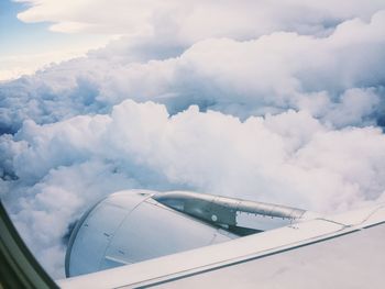 Cropped image of airplane flying by clouds 