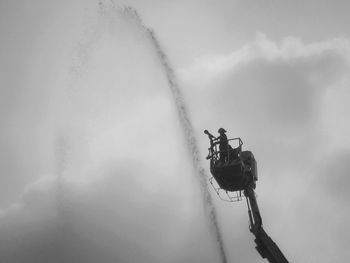 Low angle view of firefighters on hydraulic platform