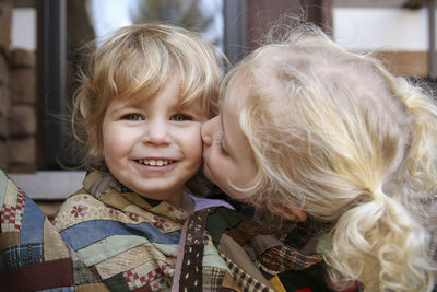 Portrait of happy girl while sister kissing her