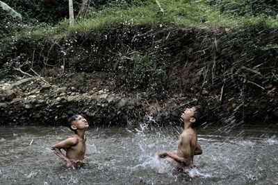 Full length of shirtless man swimming in river