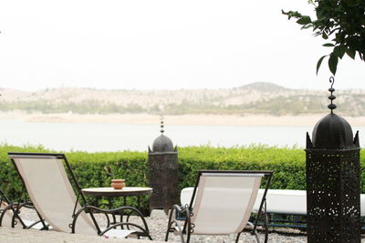 Empty chairs and table against sky