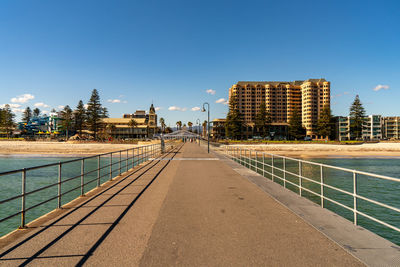 Footpath by swimming pool in city against clear sky