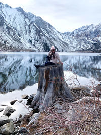 Woman standing by lake against snowcapped mountains during winter