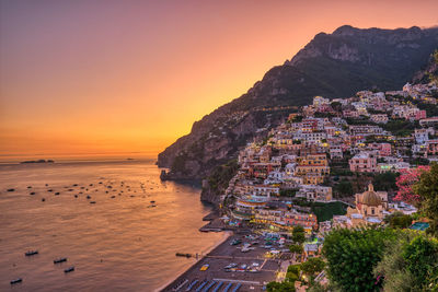 Scenic view of beach by buildings against sky during sunset