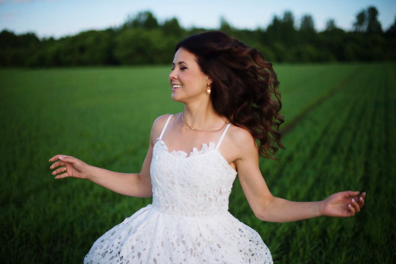 SMILING YOUNG WOMAN STANDING ON LAND DURING RAINY DAY