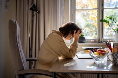 Side view of young woman using mobile phone at home