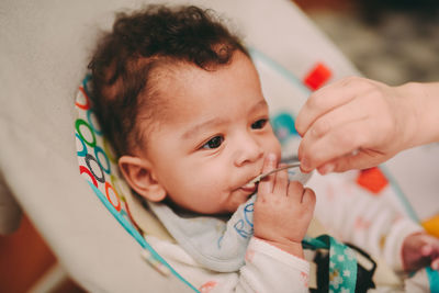 Cropped hand of mother feeding baby at home