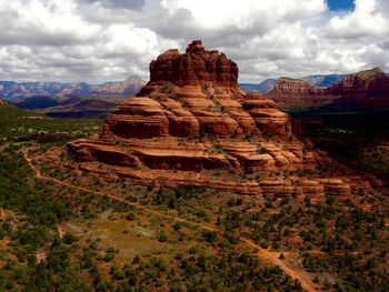 Rock formations on landscape against cloudy sky