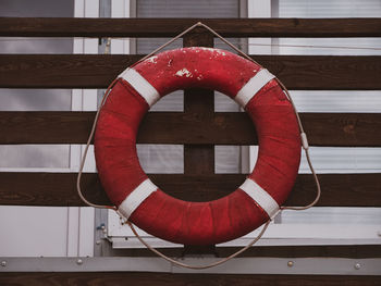 Old retro red lifebuoy hanging on wooden balcony. help, rescue concept.  vintage life saver