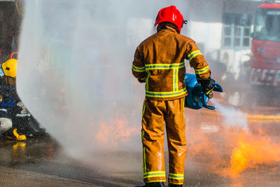 Rear view of firefighter extinguishing fire