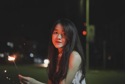 Portrait of beautiful woman holding sparkler at night